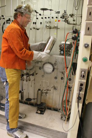 Ralf Haiges in 'typischer Arbeitskleidung'. Im Hintergrund sind Vakuumapparaturen aus Glas und Edelstahl zu sehen.